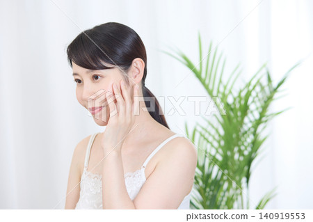 A woman with beautiful skin smiles while touching her cheek. A woman with beautiful skin smiles while touching her cheek. 140919553
