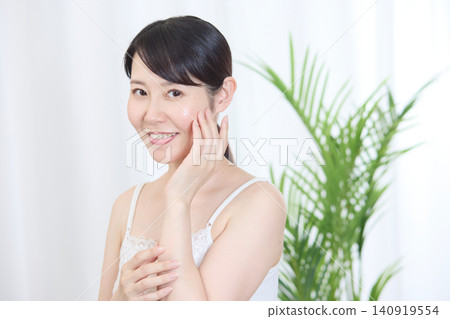 A woman with beautiful skin smiles while touching her cheek. A woman with beautiful skin smiles while touching her cheek. 140919554