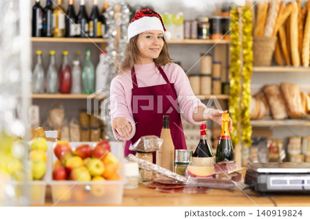 Female vendor in a Santa Claus hat offers to buy wine and other products for festive table on Christmas 140919824
