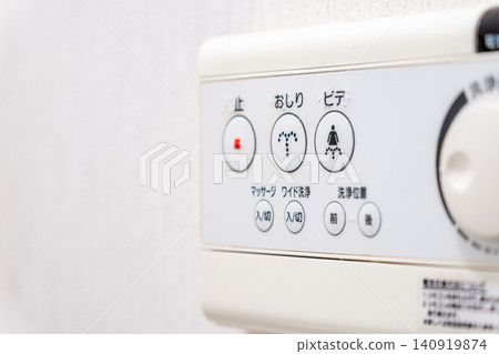 A control panel for a heated toilet seat installed on a white wall. A control panel for a heated toilet seat installed on a white wall. 140919874