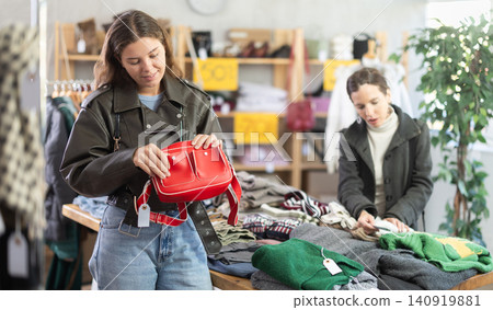 Happy girl chooses fashionable bag in clothing store Happy girl chooses fashionable bag in clothing store 140919881