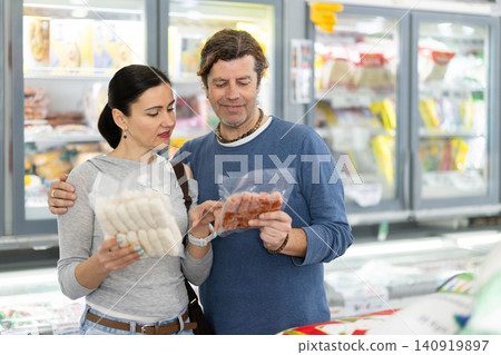 Adult couple choosing frozen sausages in grocery store Adult couple choosing frozen sausages in grocery store 140919897