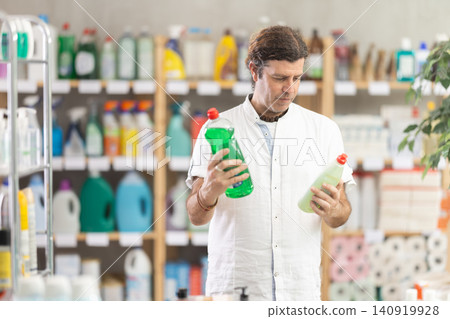 Adult man chooses dishwashing detergent in store 140919928