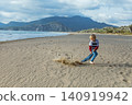 Young boy plays on Iztuzu Beach near Dalyan, Turkey, having fun, running and drawing in the sand with a stick. Active lifestyle, freedom of movement and joyful kids during summer family travel. 140919942