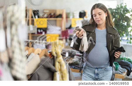 Pregnant woman choosing gloves in clothing store 140919950