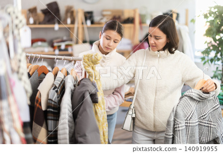 Teenage girl and her mother choose coat Teenage girl and her mother choose coat 140919955