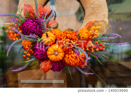Handcrafted design of Autumn Door Wreath and ornamental details against door background. Soft natural lighting orange yellow red and brown tones emphasizing the cozy character of fall home decoration Handcrafted design of Autumn Door Wreath and ornamental details against door background. Soft natural lighting orange yellow red and brown tones emphasizing the cozy character of fall home decoration 140919990