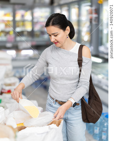 Adult woman pours rice into bag in store Adult woman pours rice into bag in store 140920071