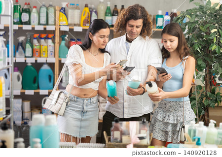 Family in summer clothes scanning QR-code on shampoo or shower gel in store Family in summer clothes scanning QR-code on shampoo or shower gel in store 140920128