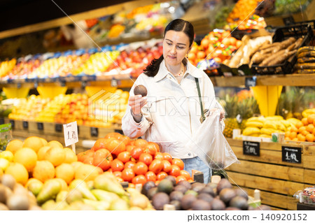 Woman shopping in grocery supermarket - choosing ripe passion fruit Woman shopping in grocery supermarket - choosing ripe passion fruit 140920152