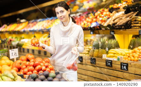 Customer puts tomatoes in a plastic bag Customer puts tomatoes in a plastic bag 140920290
