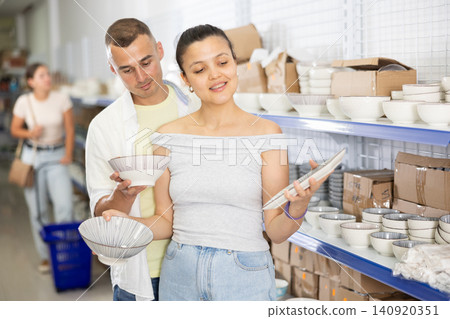 Husband and wife together choose and buy original plates for the kitchen in supermarket Husband and wife together choose and buy original plates for the kitchen in supermarket 140920351