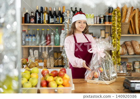 Young saleswoman is holding New Year package of products in grocery store Young saleswoman is holding New Year package of products in grocery store 140920386