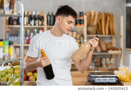 Guy carefully chooses spark wine or traditional wine in grocery store Guy carefully chooses spark wine or traditional wine in grocery store 140920423