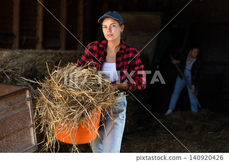 Young woman with hay bucket in barn 140920426