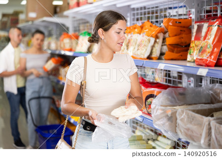 Young girl choosing Asian noodles in grocery section of supermarket Young girl choosing Asian noodles in grocery section of supermarket 140920516