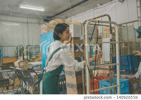 A female staff member checks the delivery slips for the carts in the back room. A female staff member checks the delivery slips for the carts in the back room. 140920556