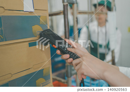 超市後倉裡,一名工作人員正用手持終端機讀取商品條碼。 超市後倉裡,一名工作人員正用手持終端機讀取商品條碼。 140920563