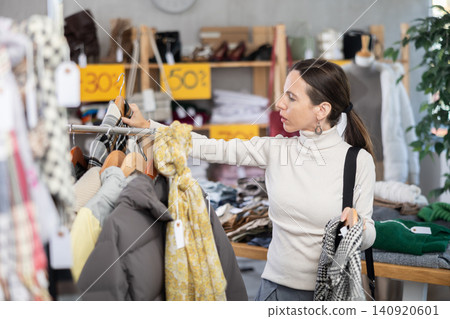 Adult woman chooses coat in clothing store Adult woman chooses coat in clothing store 140920601