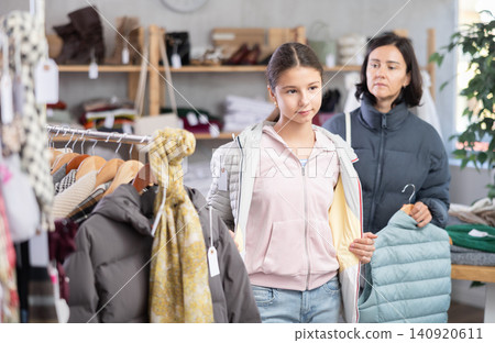Teenage girl with her mother try on down jacket Teenage girl with her mother try on down jacket 140920611