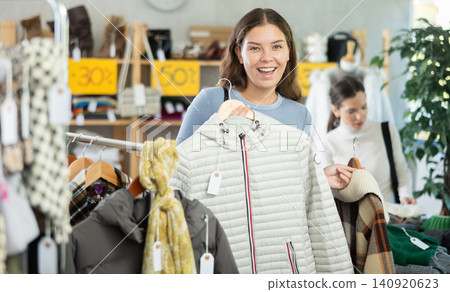 Young woman choosing down jacket in clothing store Young woman choosing down jacket in clothing store 140920623