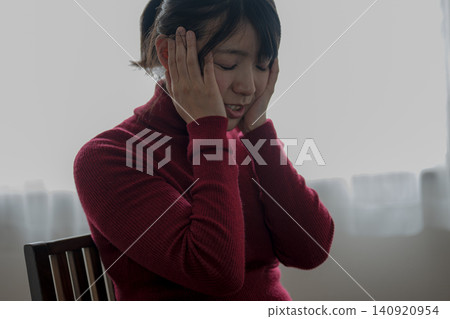 A woman in a red knit sweater suffering from a headache A woman in a red knit sweater suffering from a headache 140920954