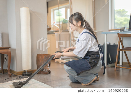 一位女士正在用吸塵器清潔地毯。 一位女士正在用吸塵器清潔地毯。 140920968