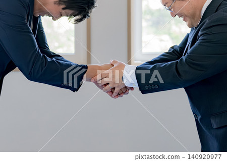 一位商人鞠躬握手。 一位商人鞠躬握手。 140920977