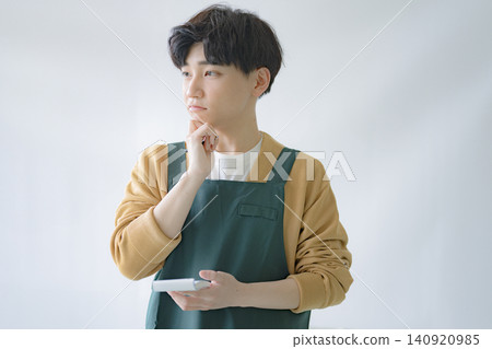 一位年輕的男性員工正在思考，手裡拿著筆記。 140920985