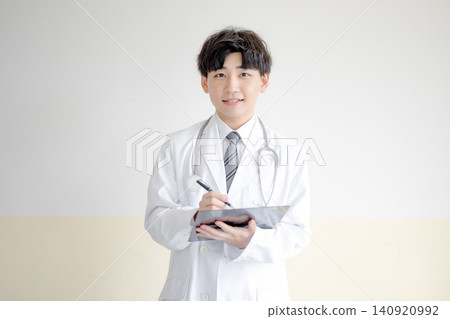 一位年輕的男醫生拿著醫療紀錄。 一位年輕的男醫生拿著醫療紀錄。 140920992