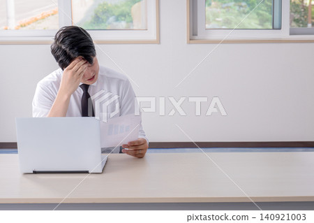 A male office worker struggling to decide what to do after reviewing the documents. A male office worker struggling to decide what to do after reviewing the documents. 140921003