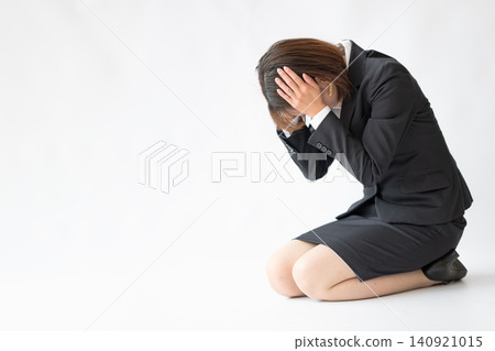 A female office worker holds her head in her hands and looks dejected. A female office worker holds her head in her hands and looks dejected. 140921015
