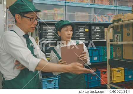 超市經理在後倉向一名兼職員工講解物品。 超市經理在後倉向一名兼職員工講解物品。 140921514