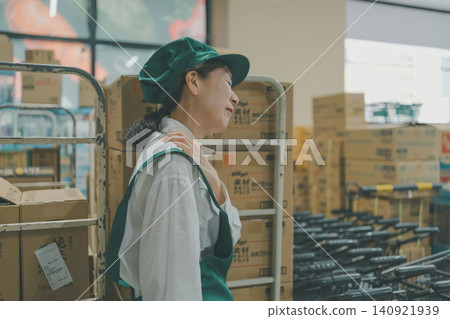 A female staff member suffering from shoulder pain in the back room. A female staff member suffering from shoulder pain in the back room. 140921939