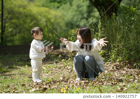 A daughter and her mother playing by throwing fallen leaves in the park. A daughter and her mother playing by throwing fallen leaves in the park. 140922757