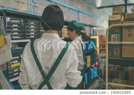 The backs of two female staff members checking shelves in the back room. The backs of two female staff members checking shelves in the back room. 140922895