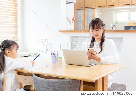 A child studying in the living room and a working mother. A child studying in the living room and a working mother. 140923003