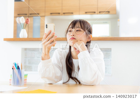 A woman troubled while watching a smartphone A woman troubled while watching a smartphone 140923017