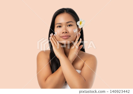 Woman performs skin care routine with beauty product on face Woman performs skin care routine with beauty product on face 140923442