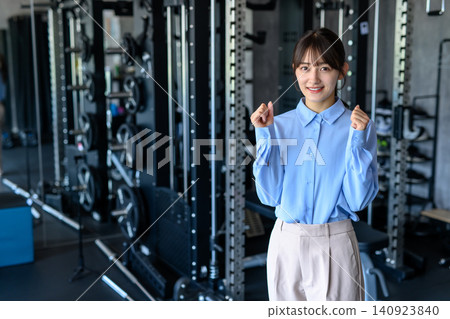 A young woman in office casual attire goes to the gym after work; a woman who works out; goes to the gym; walks. A young woman in office casual attire goes to the gym after work; a woman who works out; goes to the gym; walks. 140923840