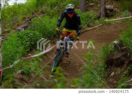 Downhill racer riding around bend Downhill racer riding around bend 140924175