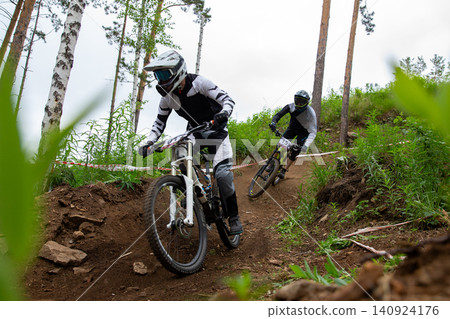 Two downhill racer riding around bend Two downhill racer riding around bend 140924176