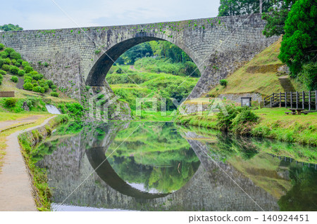 On an early autumn morning, the scenery of Tsujun Bridge is beautifully reflected on the surface of the Gorogataki River flowing beneath it. On an early autumn morning, the scenery of Tsujun Bridge is beautifully reflected on the surface of the Gorogataki River flowing beneath it. 140924451