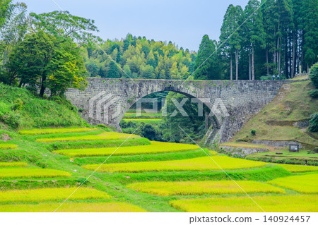 On a cloudy autumn day, a panoramic view of Tsujun Bridge from near the road overlooking it, captured with a medium telephoto lens, highlights the contrast between the terraced rice fields in the foreground and the security guard, making the wind at Tsujun Bridge stand out. On a cloudy autumn day, a panoramic view of Tsujun Bridge from near the road overlooking it, captured with a medium telephoto lens, highlights the contrast between the terraced rice fields in the foreground and the security guard, making the wind at Tsujun Bridge stand out. 140924457