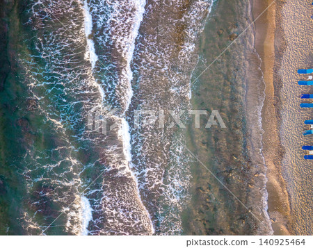 Top Down Drone View of Sea Waves and Sandy Beach with Row of Sunbeds Top Down Drone View of Sea Waves and Sandy Beach with Row of Sunbeds 140925464
