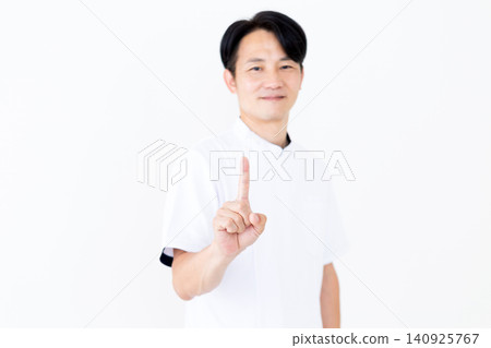 一位身穿白大褂的中年男性針灸師/整骨師,舉起他的食指。 一位身穿白大褂的中年男性針灸師/整骨師,舉起他的食指。 140925767