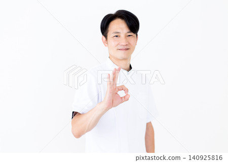 一位身穿白大褂的中年男性針灸師/整骨師擺出了一個圓圈姿勢。 一位身穿白大褂的中年男性針灸師/整骨師擺出了一個圓圈姿勢。 140925816