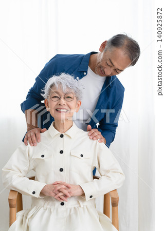 A woman sitting on a chair and a man standing next to her. Lifestyle image A woman sitting on a chair and a man standing next to her. Lifestyle image 140925872