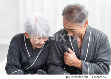 一對老年夫婦穿著長袍坐在床上,生活方式圖片 一對老年夫婦穿著長袍坐在床上,生活方式圖片 140925879