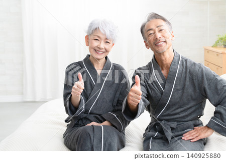 Senior couple sitting on the bed in a gown coat Lifestyle image Senior couple sitting on the bed in a gown coat Lifestyle image 140925880